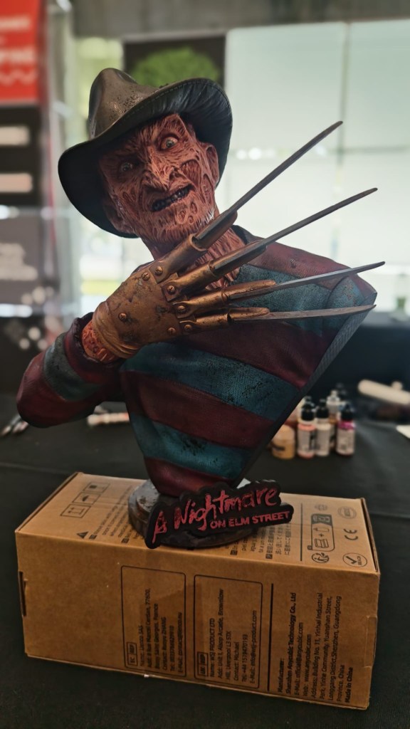 Escultura de Freddy Krueger de la película 'A Nightmare on Elm Street', mostrando su rostro expresivo y guantes con cuchillas, sobre una caja en una mesa.